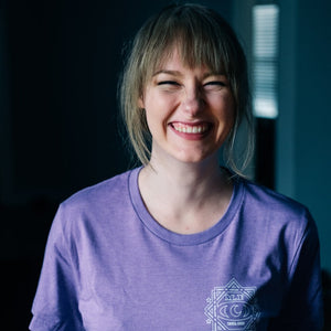 There is a smiling picture of a female model wearing the purple version of the shirt.