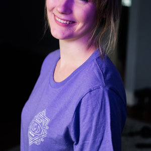 There is a smiling picture of a female model wearing the purple version of the shirt.